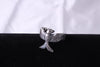 A detailed shot of a silver ring with an anatomically accurate silhouette of a bird. High detail of the metal and mirror polish on a contrasting black background.
