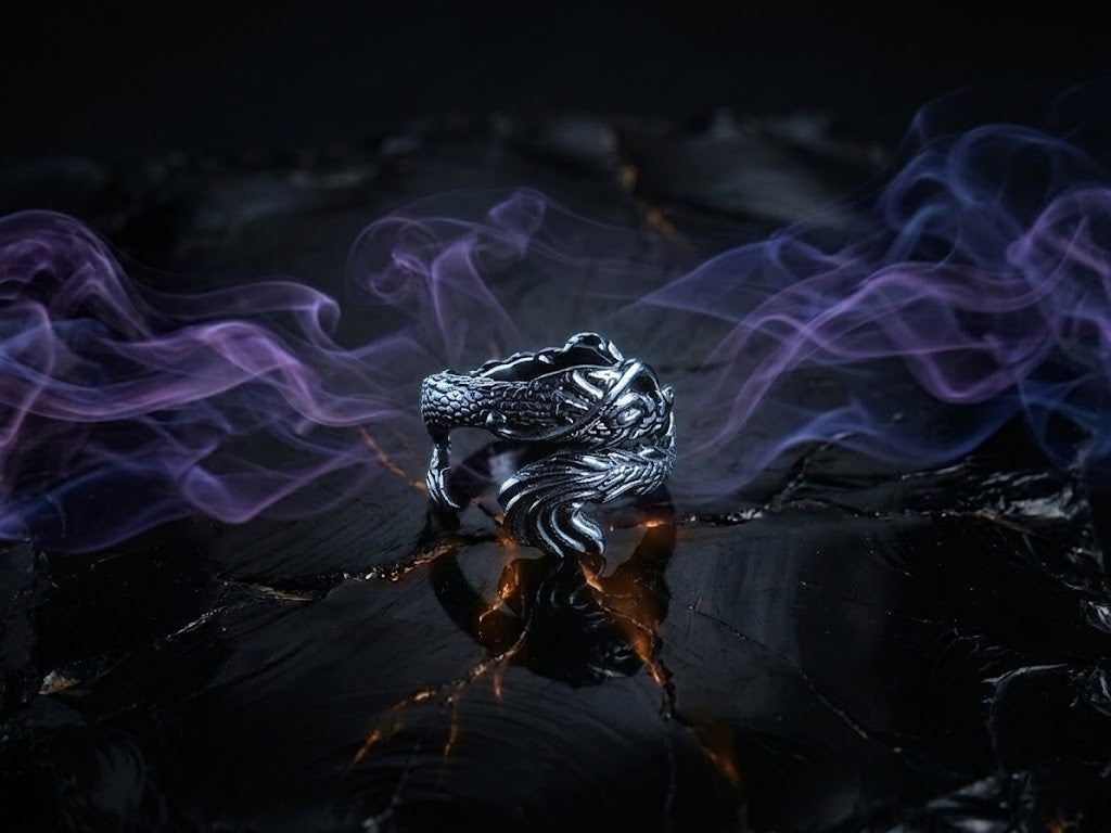 Detailed sterling silver statement ring featuring a dragon design on an obsidian base with stylized lighting.