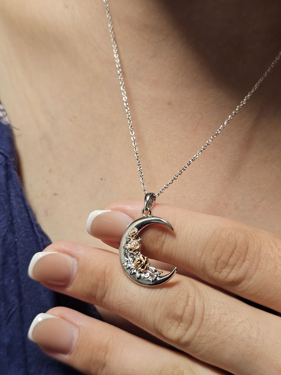 Close-up of a 925 sterling silver crescent moon necklace with sculpted rose and leaf details.