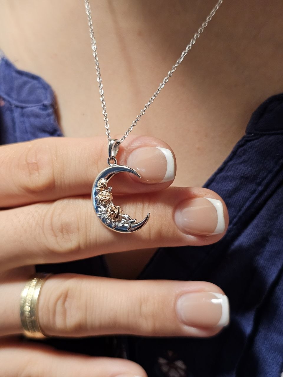 Crescent moon rose 925 sterling silver necklace held by hand to show pendant size and details.
