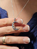 Crescent moon rose 925 sterling silver necklace held by hand to show pendant size and details.