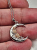 Crescent moon rose 925 sterling silver necklace held by hand to show pendant size and details.