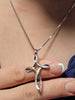 Close-up of a 925 sterling silver cross necklace with iridescent enamel accents and Faith Hope Love inscription.