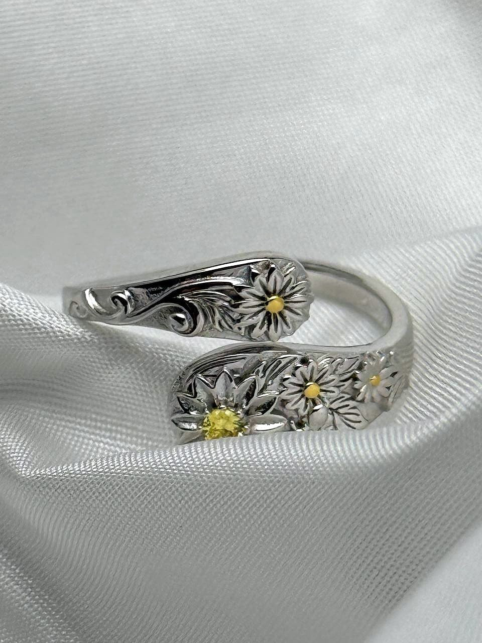 Detailed view of sterling silver floral ring with yellow zircon and golden-tone flower accents
