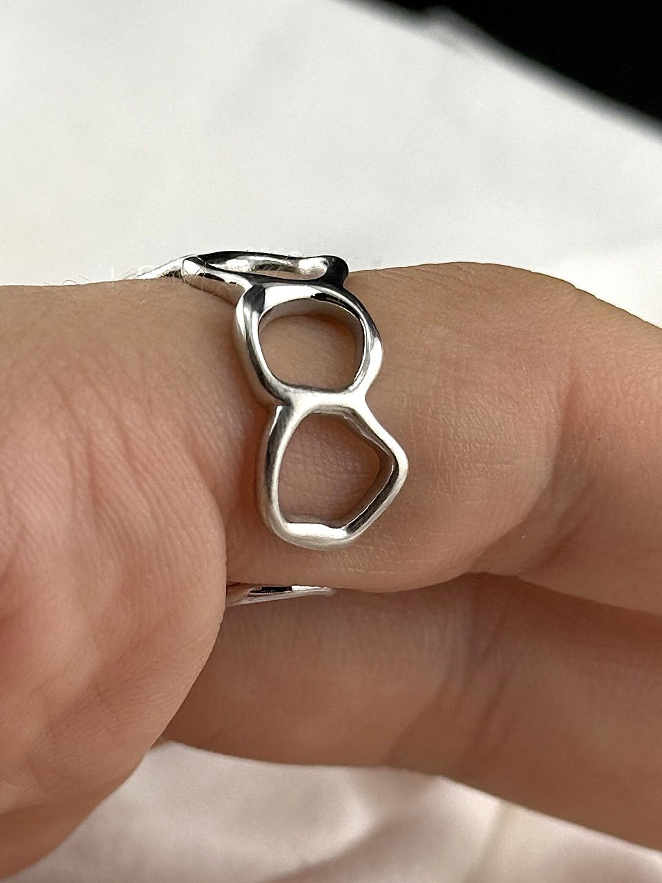 Close-up of adjustable sterling silver ring showing its flowing open circle design and polished finish