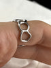Close-up of adjustable sterling silver ring showing its flowing open circle design and polished finish
