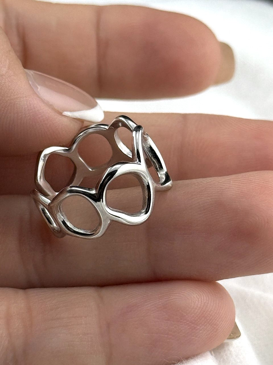 Close-up of a polished sterling silver ring with flowing open circle design