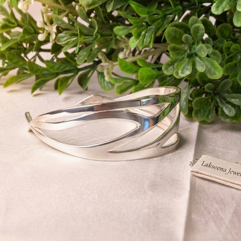 Headwind sterling silver cuff bracelet with Lakseena Jewelry tag on a natural green background, Sacred Bloom Collection.
