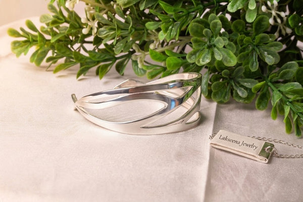 Headwind sterling silver cuff bracelet with Lakseena Jewelry tag on a natural green background, Sacred Bloom Collection.
