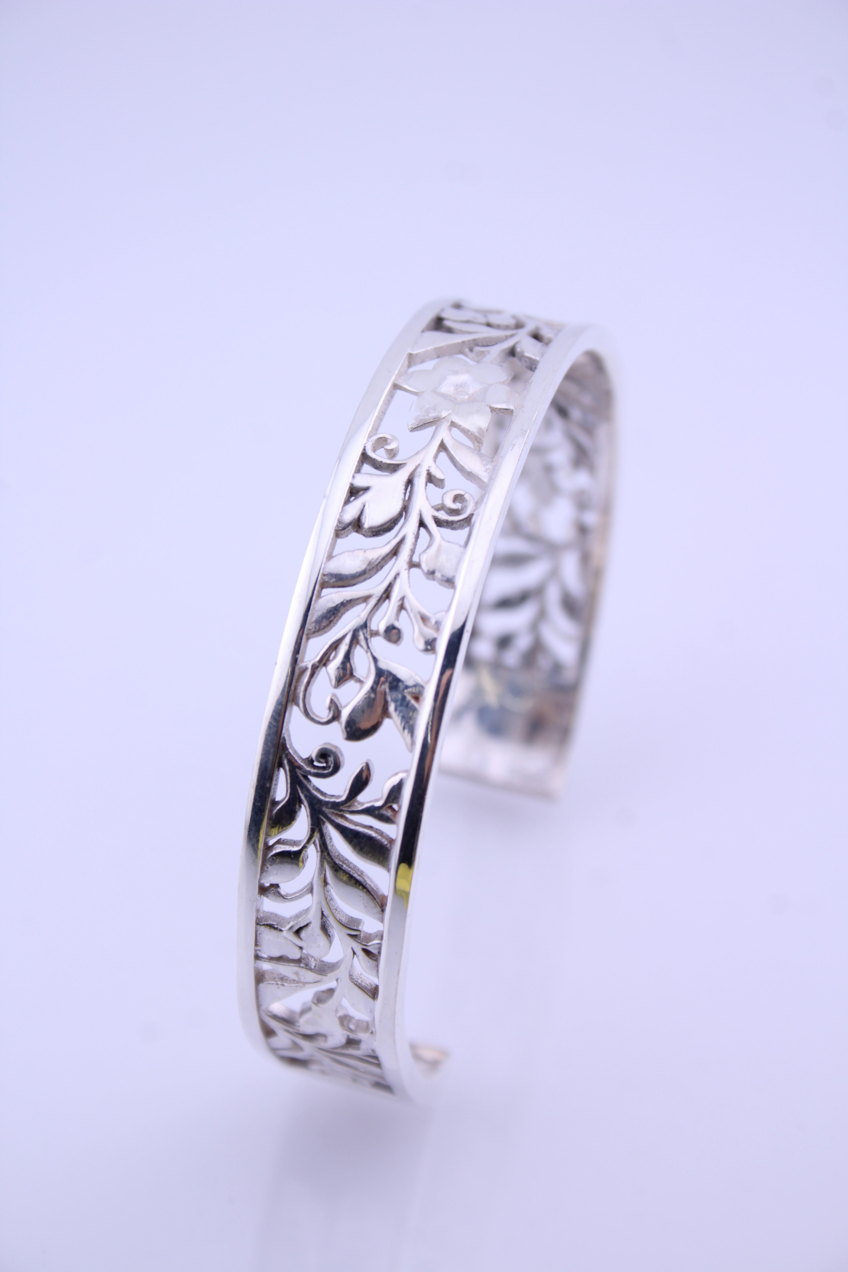 "Sterling silver floral vine cuff bracelet shown upright with detailed engraved pattern on white background"