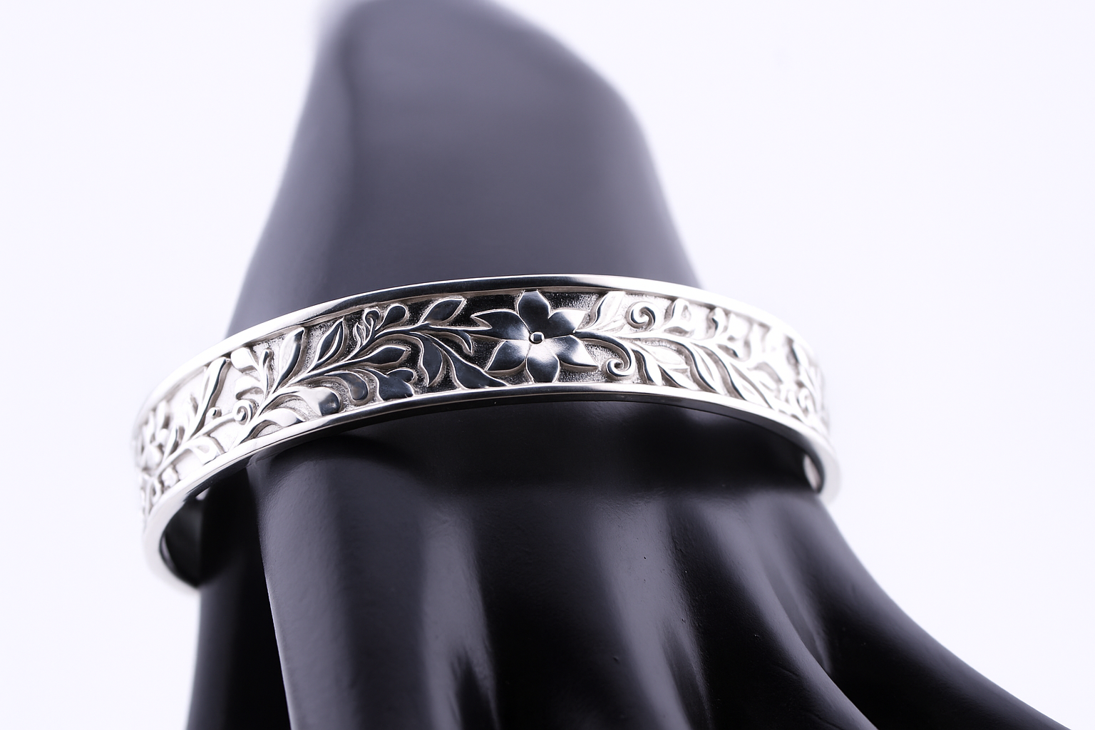 "Royal silver cuff bracelet with floral flower engraving displayed on a black mannequin hand — luxury sterling silver jewelry by Lakseena."