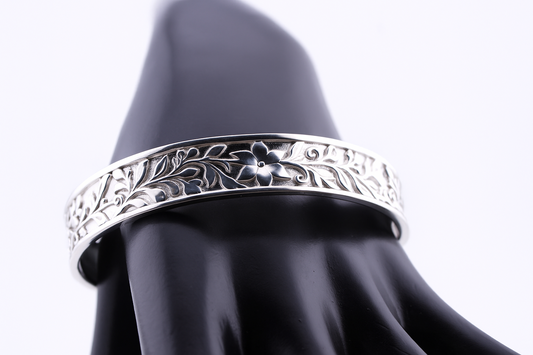 "Royal silver cuff bracelet with floral flower engraving displayed on a black mannequin hand — luxury sterling silver jewelry by Lakseena."