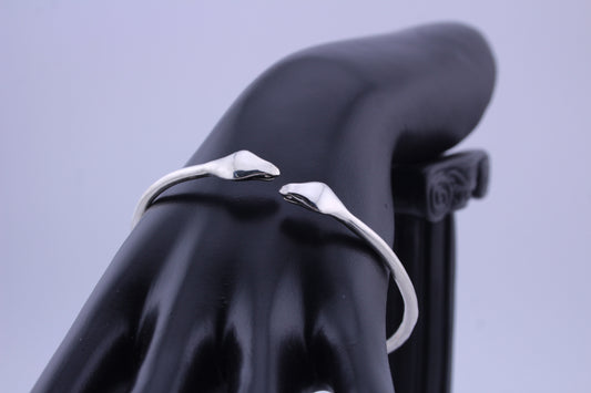 "Silver twin cobra cuff bracelet on black mannequin hand, sculpted snake heads facing each other in an open cuff design."