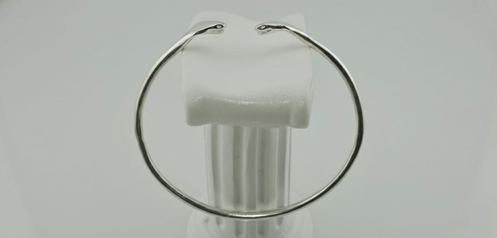 "Side view of 925 sterling silver cuff bracelet with twin sculpted serpentine design on white background."