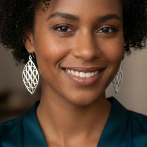 Woman wearing minimalist sterling silver leaf-shaped dangle earrings with openwork pattern