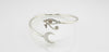 sterling silver cuff bracelet with engraved eye and crescent moon design, photographed on a light background