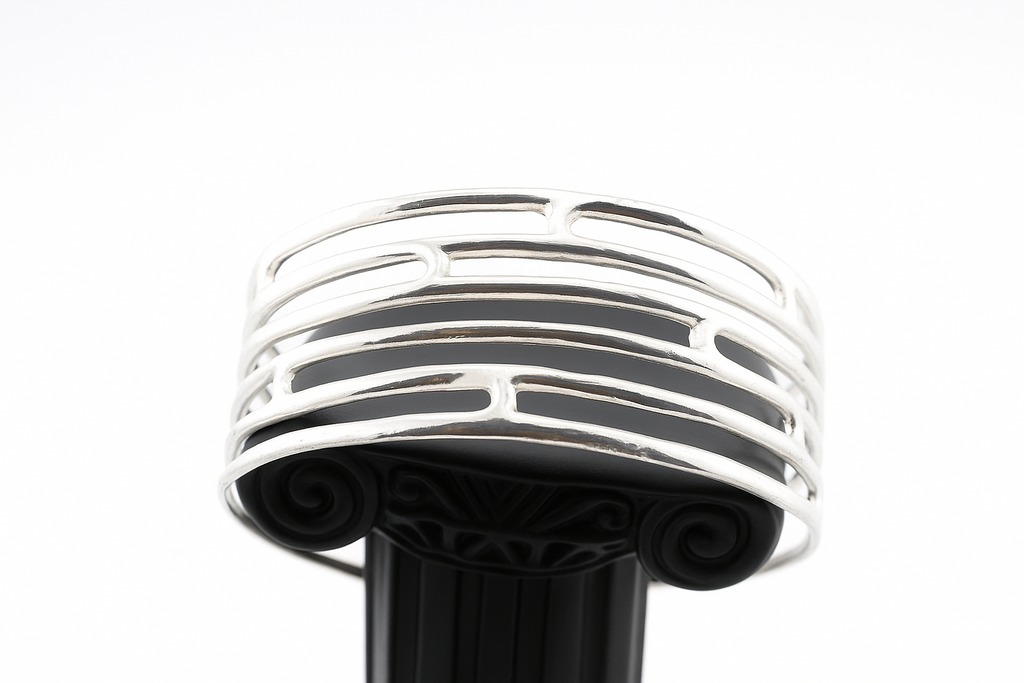 Bottom angle view of sterling silver openwork cuff bracelet on display pedestal