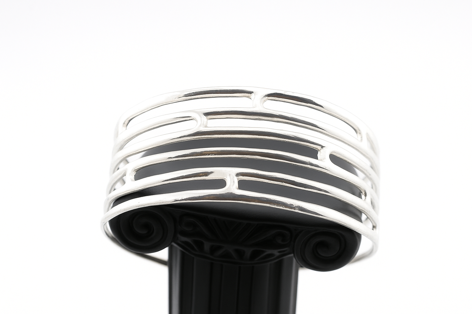 Bottom angle view of sterling silver openwork cuff bracelet on display pedestal