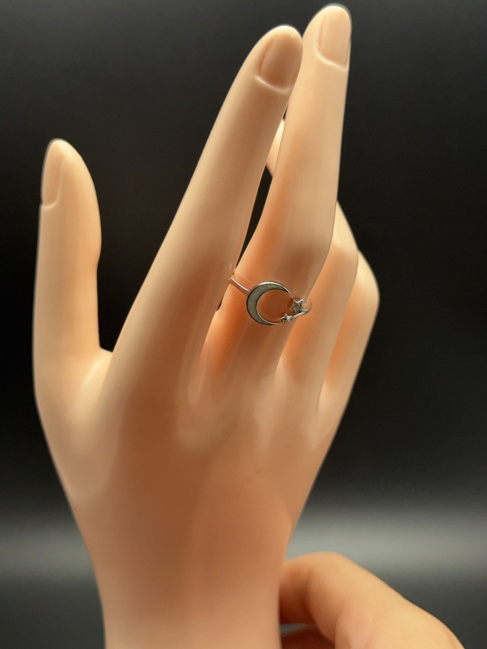 Adjustable sterling silver crescent moon and stars ring with opal inlay shown on finger