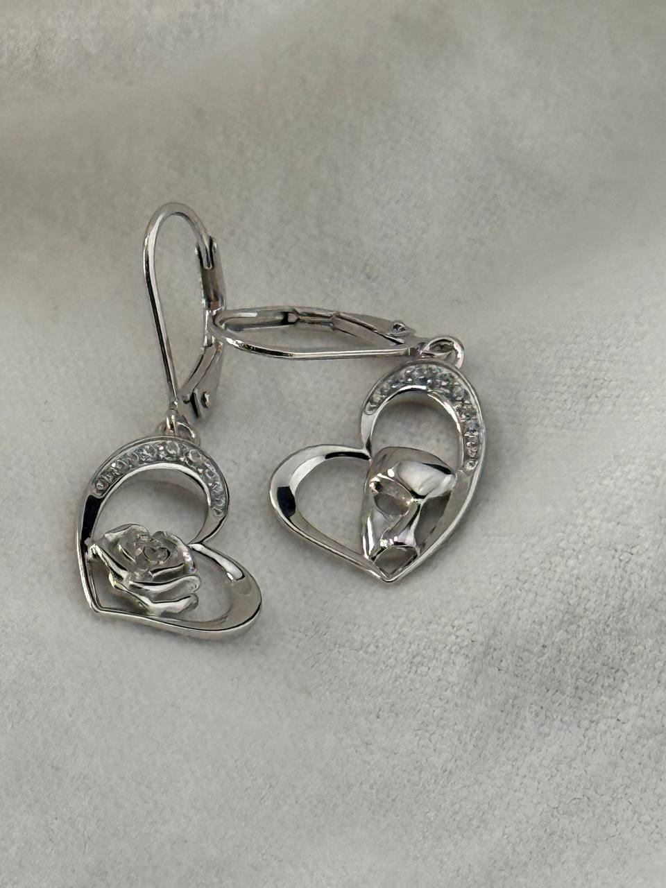 Close-up of sterling silver heart earrings with rose and masquerade mask details and cubic zirconia accents