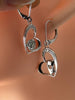 Close-up of sterling silver rose and masquerade heart earrings showing polished details and sparkling stone accents