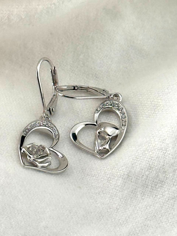 Front view of sterling silver heart earrings featuring a rose and masquerade mask with sparkling stone accents