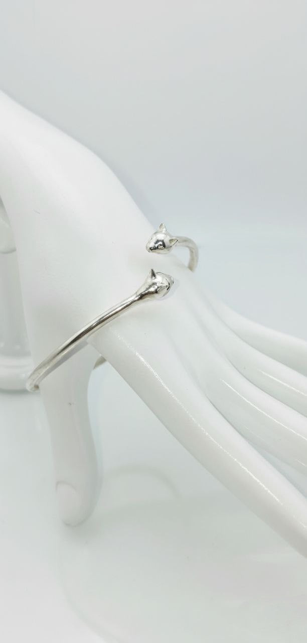 “Silver Cat Bracelet – vertical close-up of 925 sterling silver open cuff with twin cat heads on a white mannequin hand”