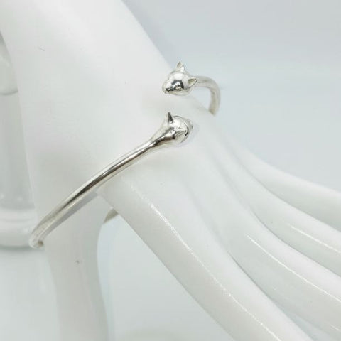“Silver Cat Bracelet – vertical close-up of 925 sterling silver open cuff with twin cat heads on a white mannequin hand”