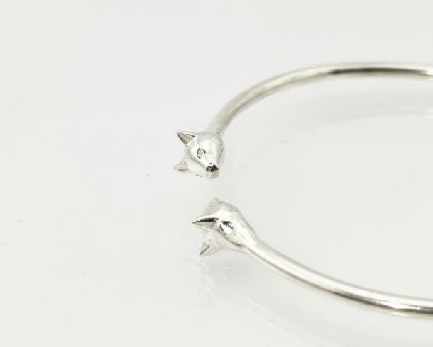 “Silver Cat Bracelet – angled view of 925 sterling silver open cuff with twin cat head tips on a white background”