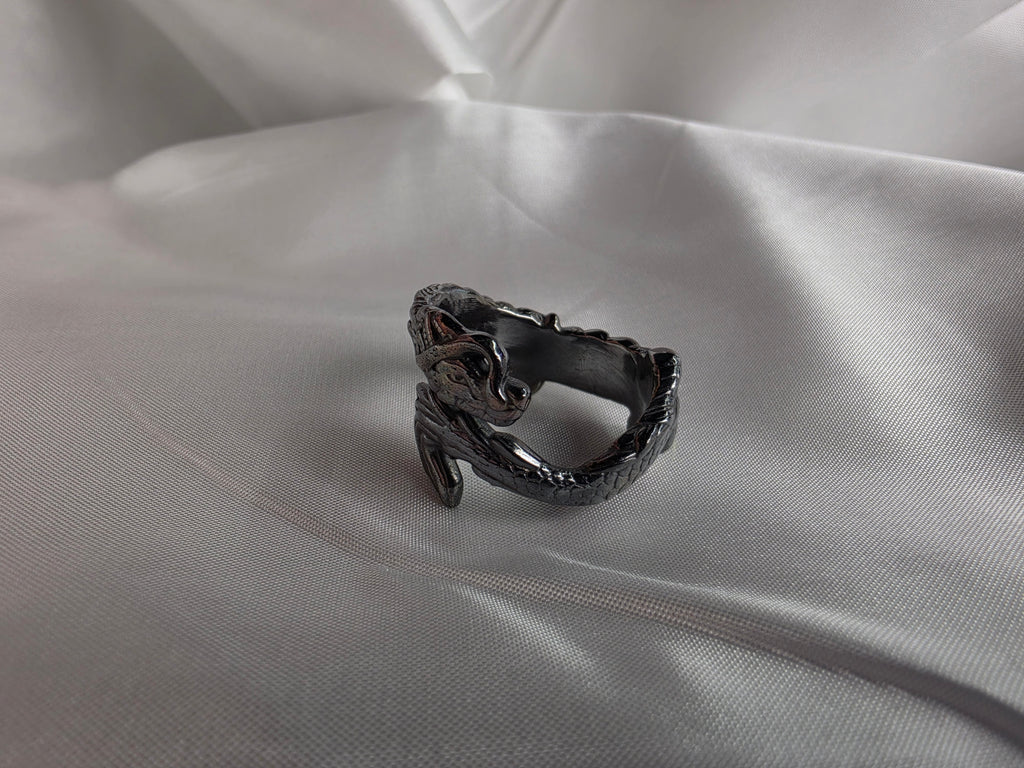 Oxidized sterling silver dragon ring with hand-polished finish on white satin.