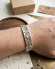 Handcrafted 925 sterling silver floral cuff bracelet shown on a wrist, featuring intricate openwork design and heritage artistry. Elegant jewelry for daily wear by Lakseena.