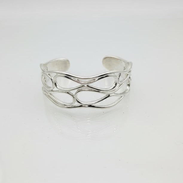 Silver openwork cuff bracelet with infinity wave pattern on a white background.