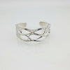 Silver openwork cuff bracelet with infinity wave pattern on a white background.
