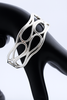Silver openwork infinity cuff bracelet displayed on a black mannequin arm.