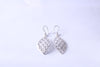 Pair of handcrafted sterling silver leaf earrings with an openwork design on a white background
