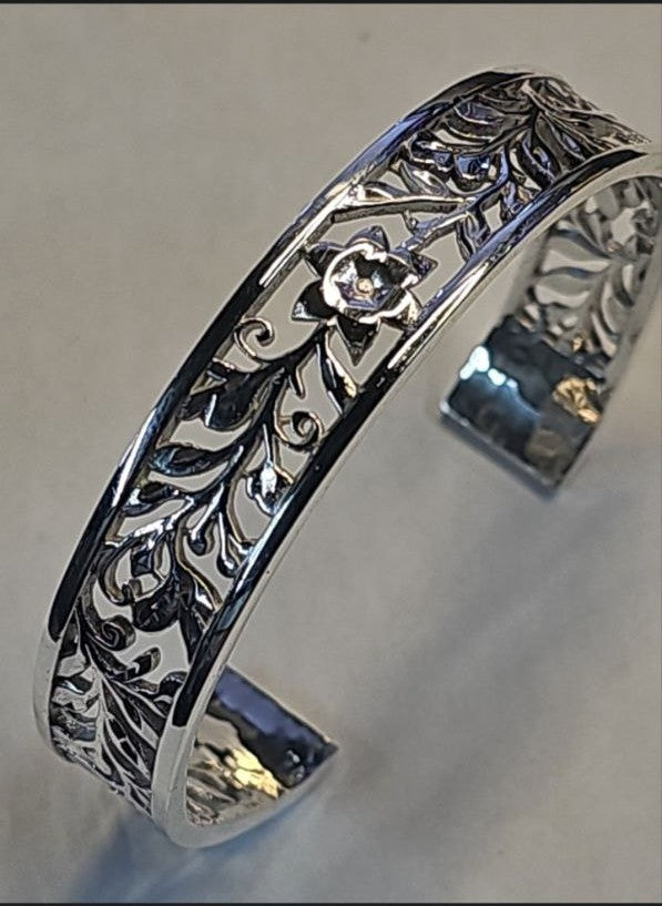 Close-up of a 925 sterling silver cuff bracelet with intricate, high-relief floral engraving, featuring a brilliant mirror-like polish. Perfect 3D printing craftsmanship by Lakseena Jewelry.
