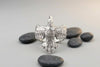 Unisex ring 'Raven' made of polished silver. A symbol of wisdom and heritage in a modern jewelry design. Composition with stones on a gray background.