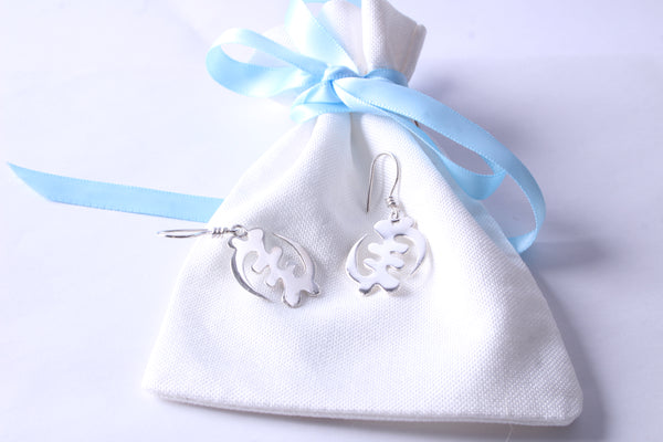 Handcrafted sterling silver symbol dangle earrings displayed on a white gift pouch with blue ribbon
