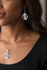 Handcrafted sterling silver symbol dangle earrings worn by a model, highlighting scale and elegant everyday style
