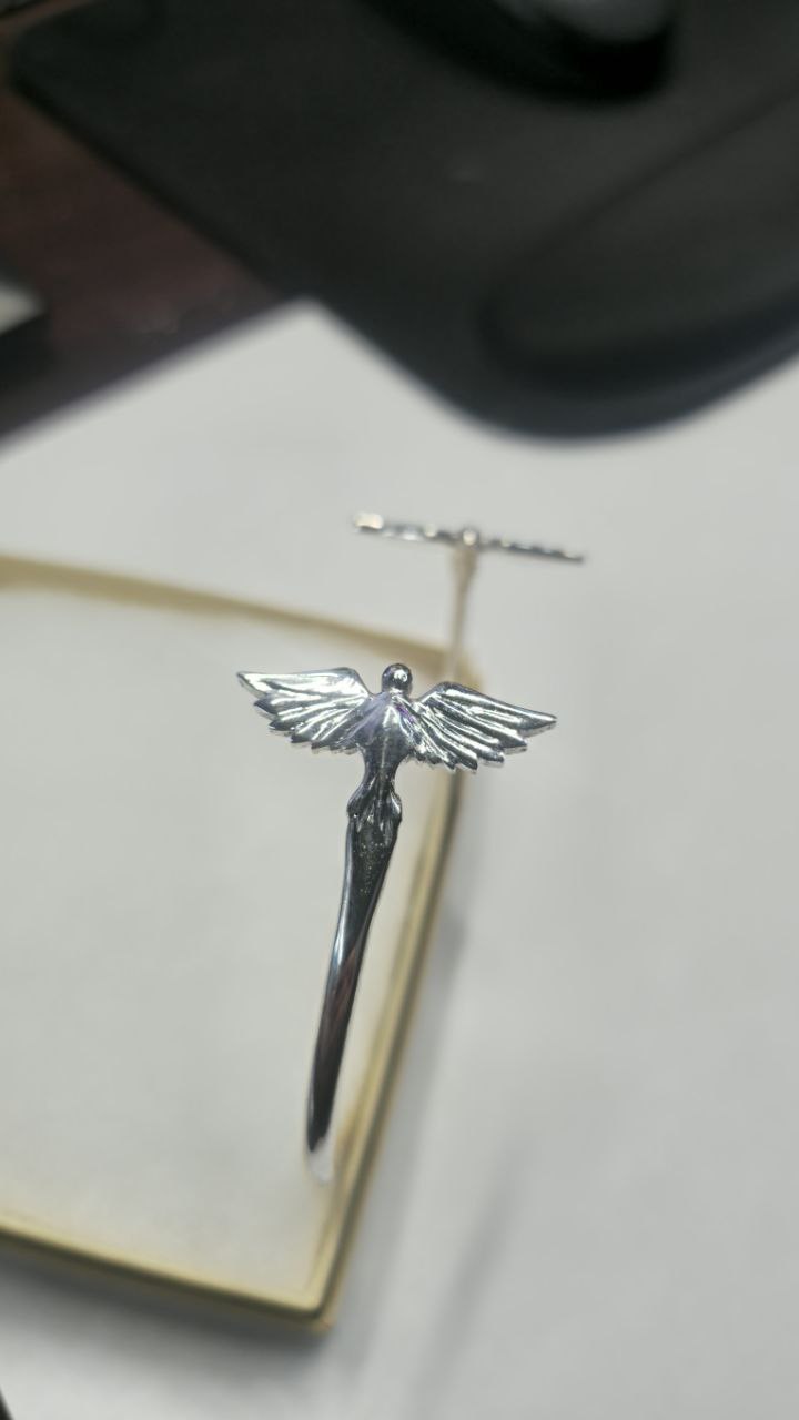 Macro shot of the Twin Wings bracelet, showcasing the unique, hand-sculpted texture of each feather. High-relief 3D design in 925 sterling silver with a brilliant finish by Lakseena Jewelry.

