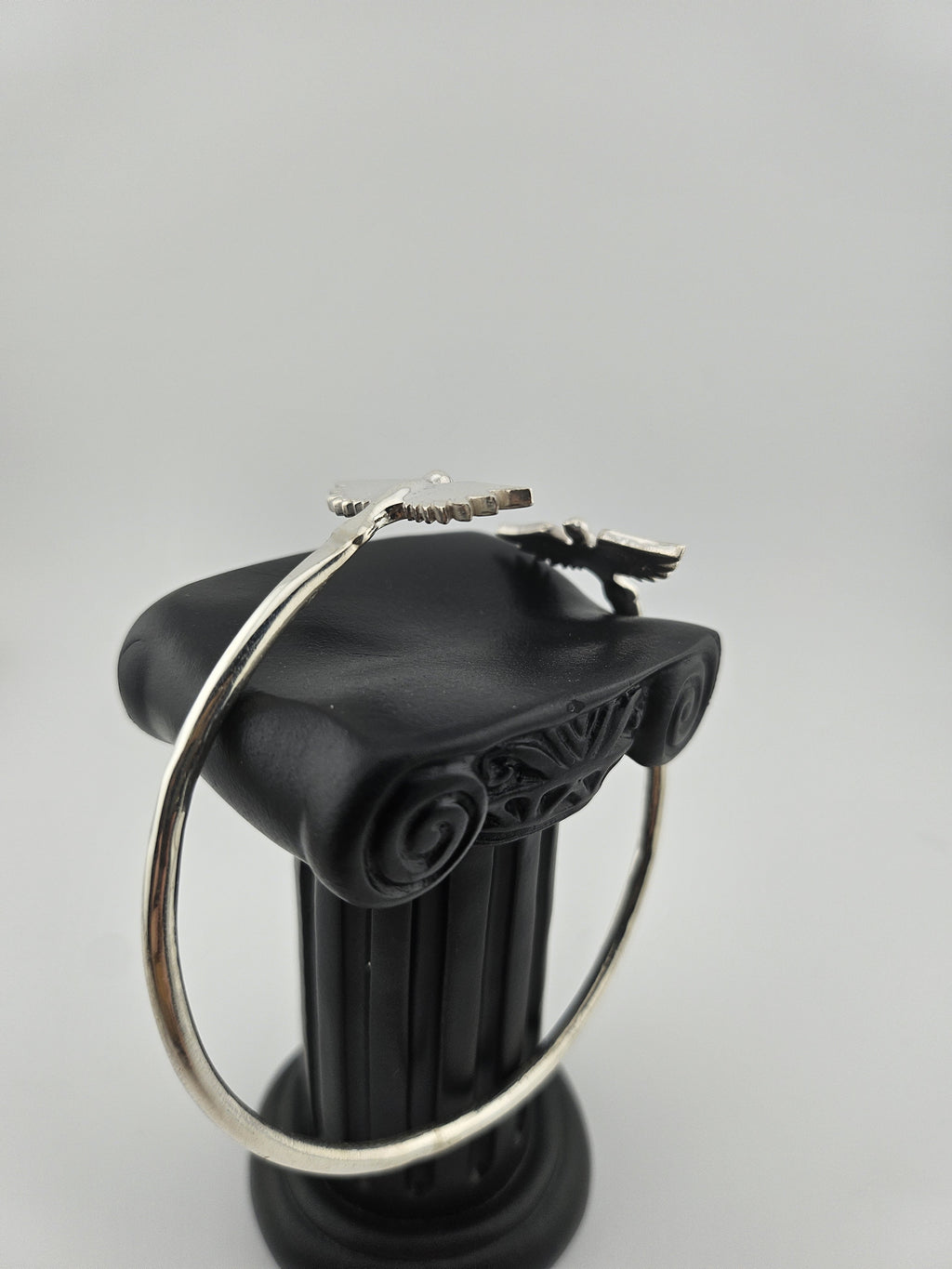 “side view of 925 sterling silver bird-wing cuff bracelet displayed on black jewelry stand”