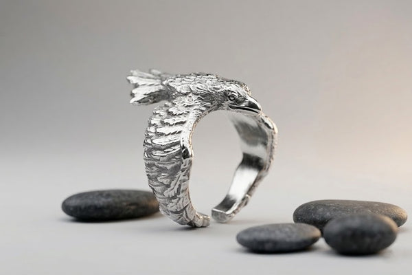 Detailed ring made of 925 sterling silver in the shape of a raven, unisex design. Wrapping wings create a textured band. Minimalist style, handmade.