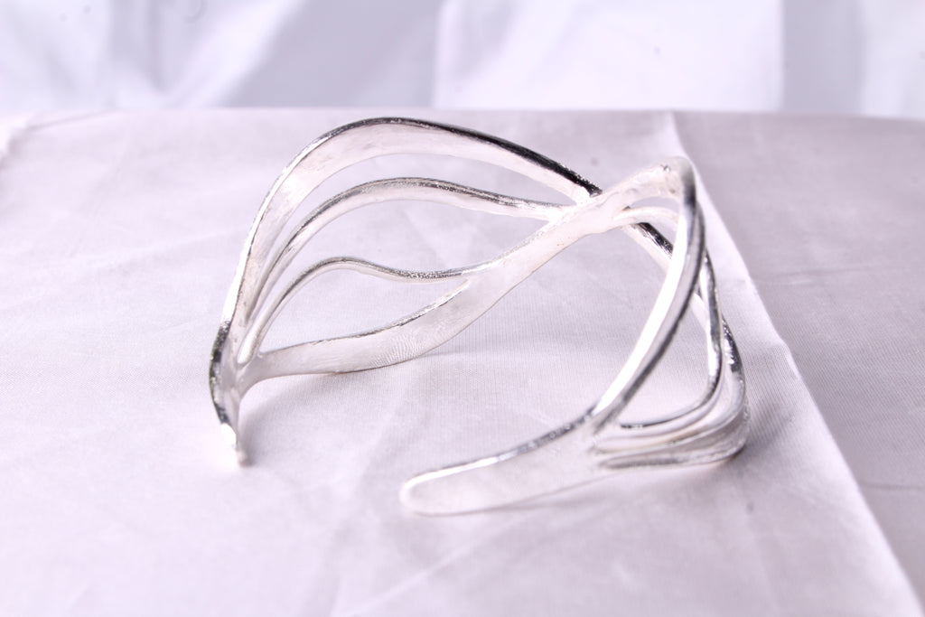 Close up of Wave silver bracelet highlighting the contrast between textured interior and mirror polished exterior